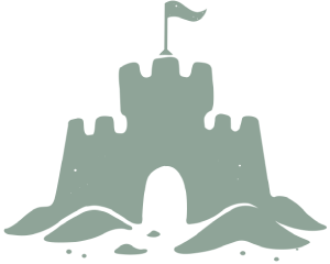 A simple sandcastle with a flag on top, built in the sand with a central arch and small mounds around, sitting on a sandy beach.